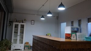 A reception area with a wooden counter, pendant lights, a white cabinet, and a refrigerator. - Parichart Place (Pua)