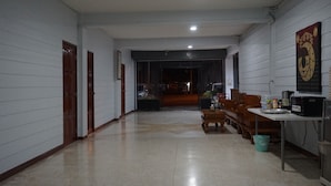 A hallway with a wooden bench, a table with a microwave, and a trash bin. - Parichart Place (Pua)