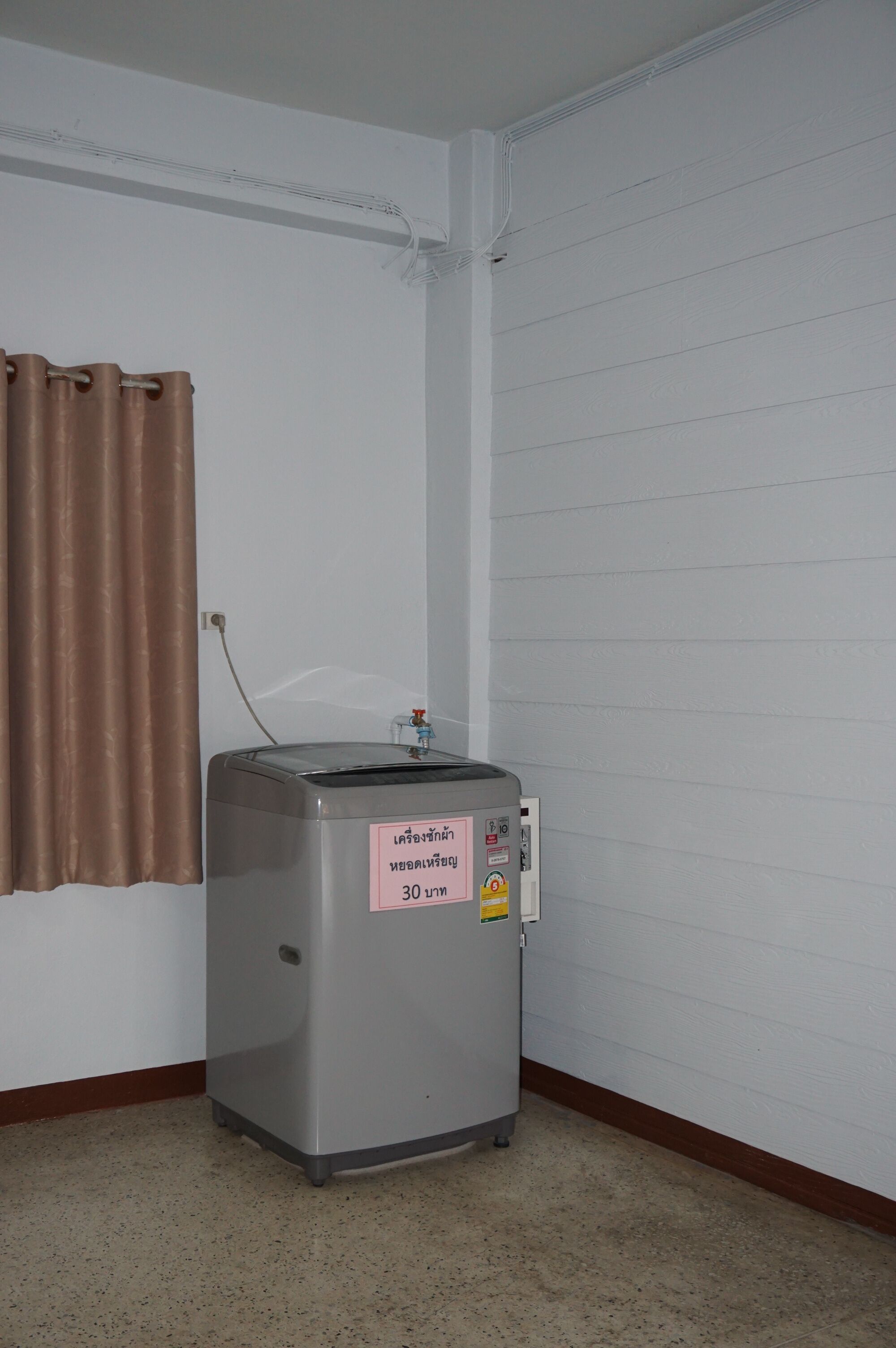 A small kitchenette with a toaster, a wall-mounted electrical outlet, and a brown curtain.