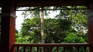 A balcony with a view of lush green trees and a clear sky. - Parichart Place (Pua)