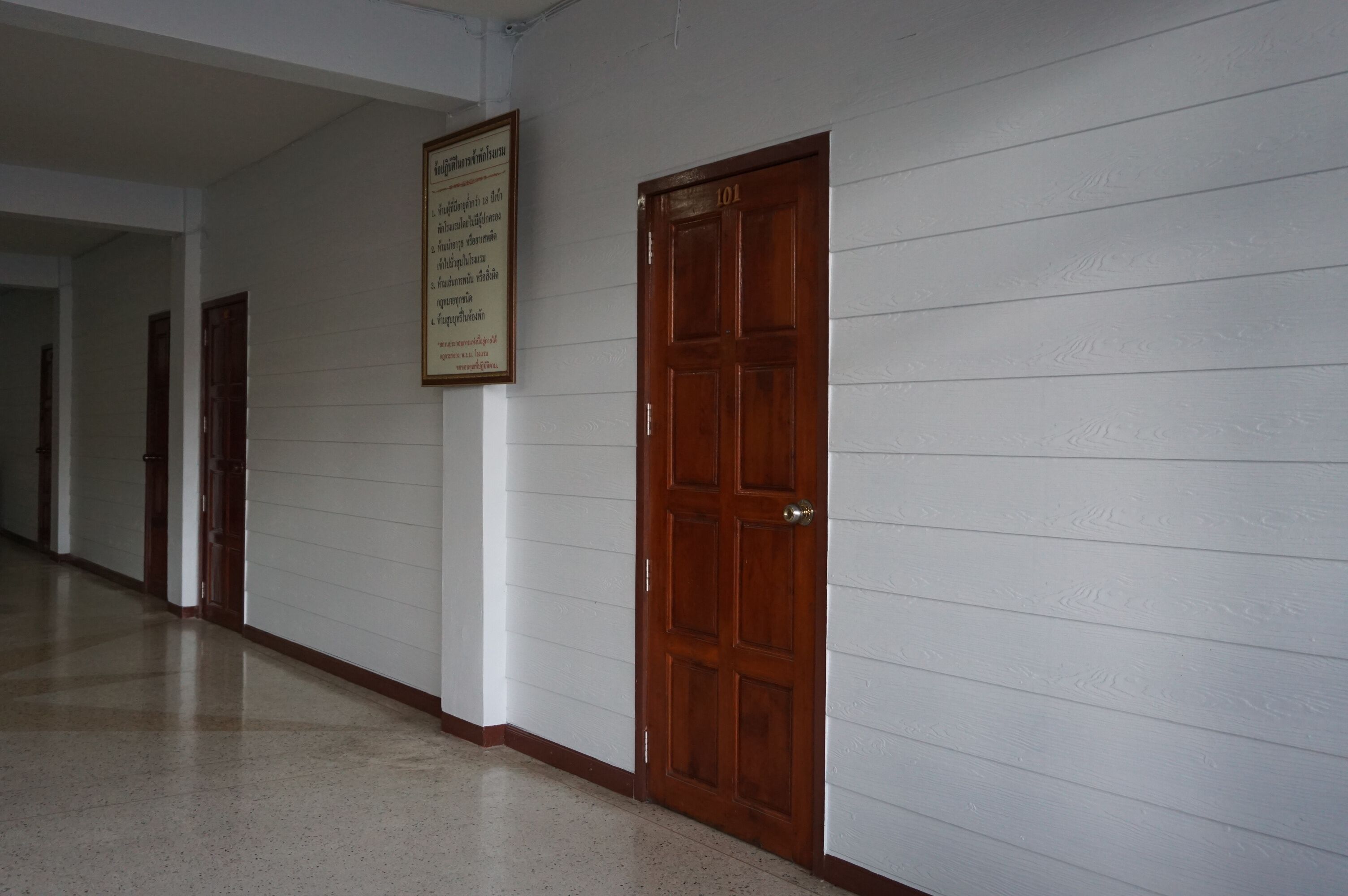 A hallway with white walls and wooden doors, including a door labeled "101".