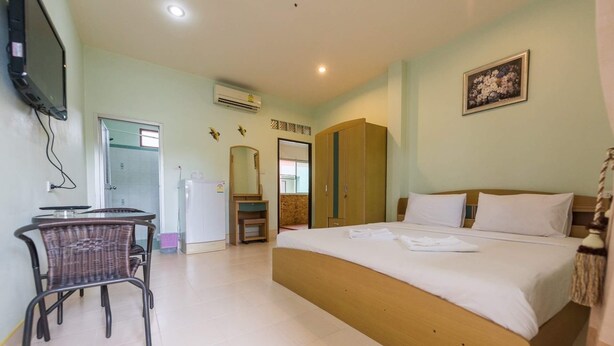 A bedroom with a bed, a desk, a chair, a wardrobe, and an air conditioning unit. - Pachumas Mansion (Karon)