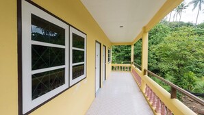 A corridor with large windows, a balcony with a railing, and a view of greenery. - Pachumas Mansion (Karon)