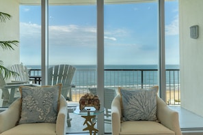 Enjoy a panoramic ocean view from the comfort of this stylish room, featuring a seating area with armchairs and a small table.