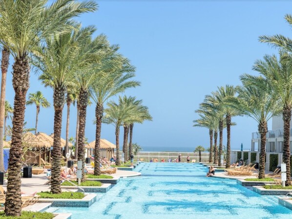 Relax by the ocean-view pool surrounded by palm trees and lounge chairs.