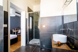 Un baño moderno con ducha de vidrio, lavamanos blanco y tocador de madera.