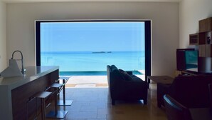 A modern living room with a large sliding glass door leading to a balcony overlooking the ocean. - SUMMER RATE Modern Beachfront 5bed - 5bath with incredible view (providenciales)
