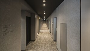 A hotel hallway with a carpeted floor, multiple doors, and a sign indicating guest rooms 101-116. - Hotel R9 Sano Fujioka (Sano)