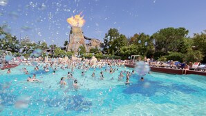 Una gran piscina al aire libre con gente nadando y tomando el sol.