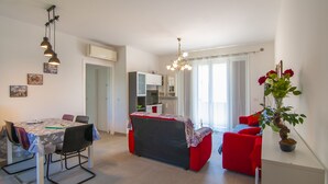 Un espacio habitable moderno con comedor, cocina y un sofá rojo.