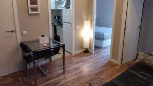 A compact room with a bed, a desk, and a kitchenette.
