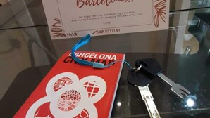 A welcome sign for Barcelona, a red booklet with the Barcelona Hotel Association logo, and a set of keys on a glass table.