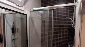 A modern bathroom with a glass shower enclosure, a white sink, and a large mirror.