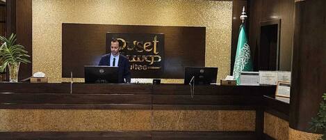 A reception desk with a sign reading "Dusit Hotel" and a flag.