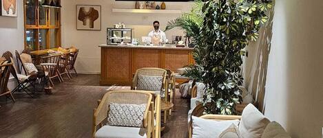 A cozy restaurant interior with wooden furniture, a bar area, and a large green plant.