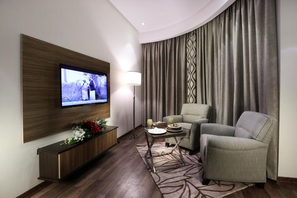 Un salon moderne avec un téléviseur à écran plat fixé sur un panneau en bois, un canapé, une table basse et un lampadaire.