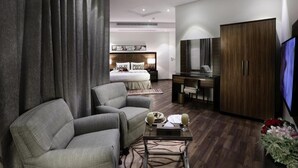 Una habitación de hotel moderna con una cama, un sofá, un escritorio, un televisor y un armario.