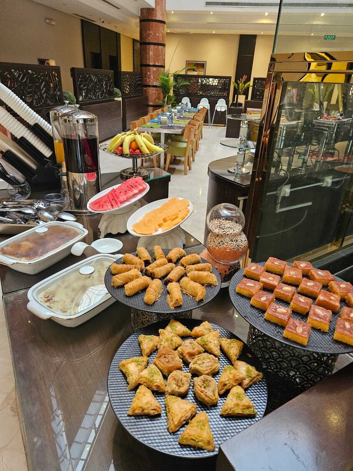 A buffet with various dishes, including pastries and fruits, in a modern hotel setting.