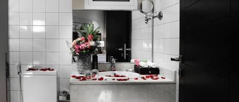 A bathroom with a white sink, a mirror, and a vase with flowers.