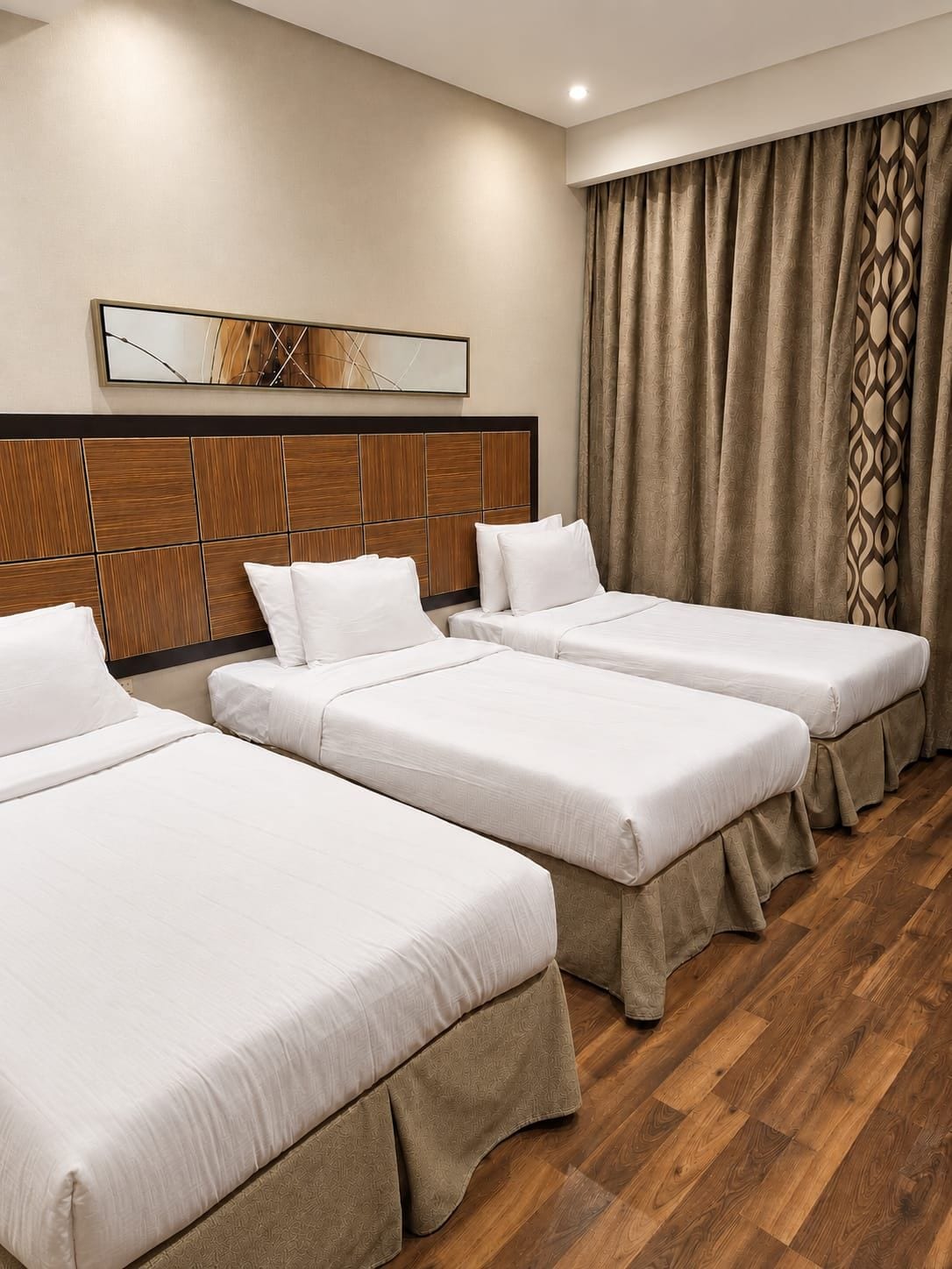A hotel room with three single beds, a wooden headboard, a large mirror, and a window with curtains.