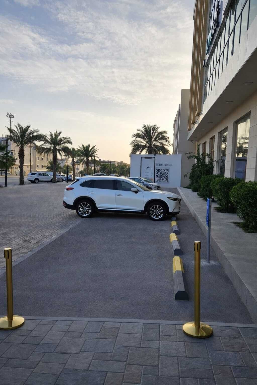 A white car parked in a paved area with a building in the background.