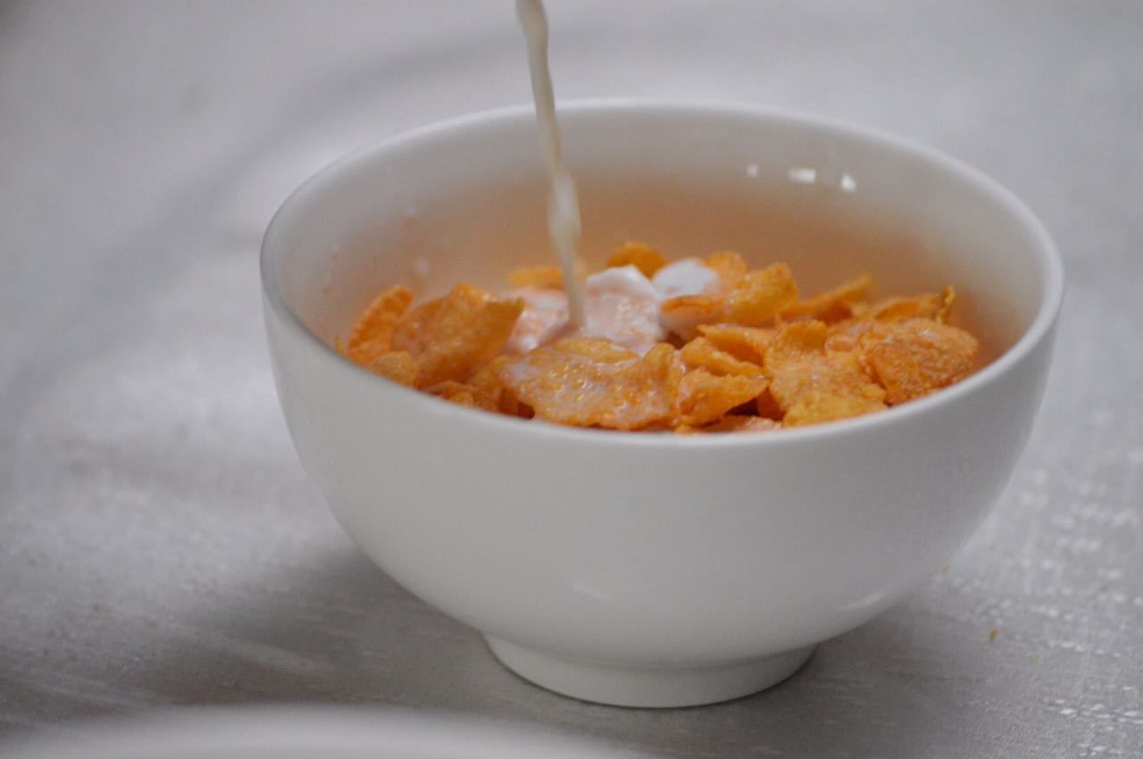 A bowl of cereal with milk being poured into it.