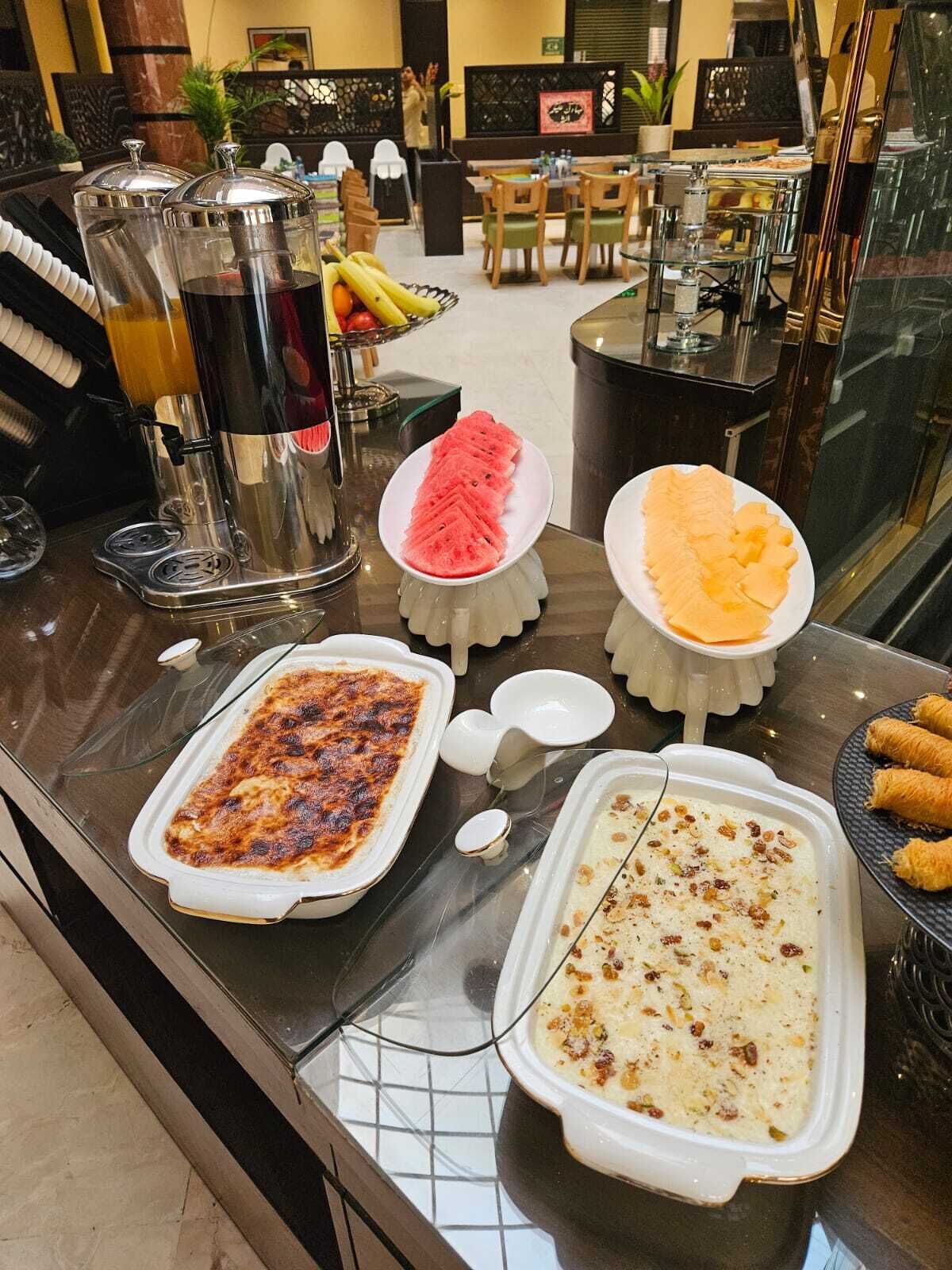 A buffet with various dishes, a coffee machine, and a seating area with tables and chairs.