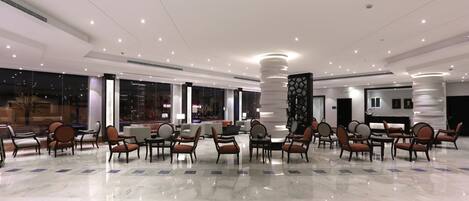 A spacious lobby with a polished marble floor, numerous seating areas, and a modern ceiling design.
