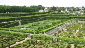 Un jardin à la française, caractérisé par des motifs géométriques, des haies taillées avec soin et une fontaine ou un bassin central.