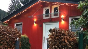 Ein rotes Gebäude mit einer weißen Tür, einem kleinen Fenster und der Nummer 36 an der Wand.