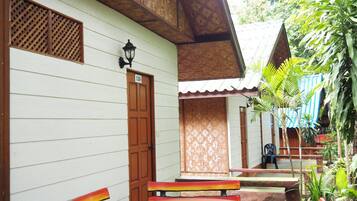 Una casa con puerta de madera que tiene el número 139, un pequeño porche con un banco y una mesa redonda.