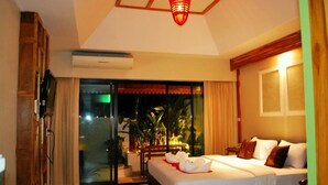 A hotel room with a bed, a desk, and a view of the outdoors. - Oopkaew Resort (Pua)