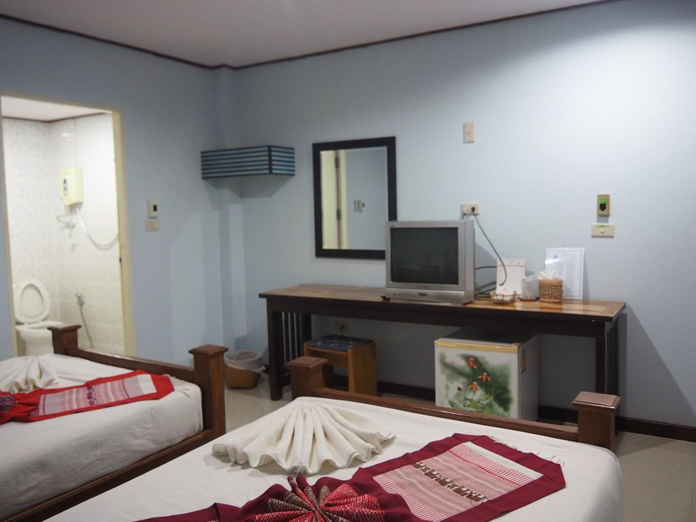 A hotel room with two beds, a desk with a computer, a mirror, and a small table.