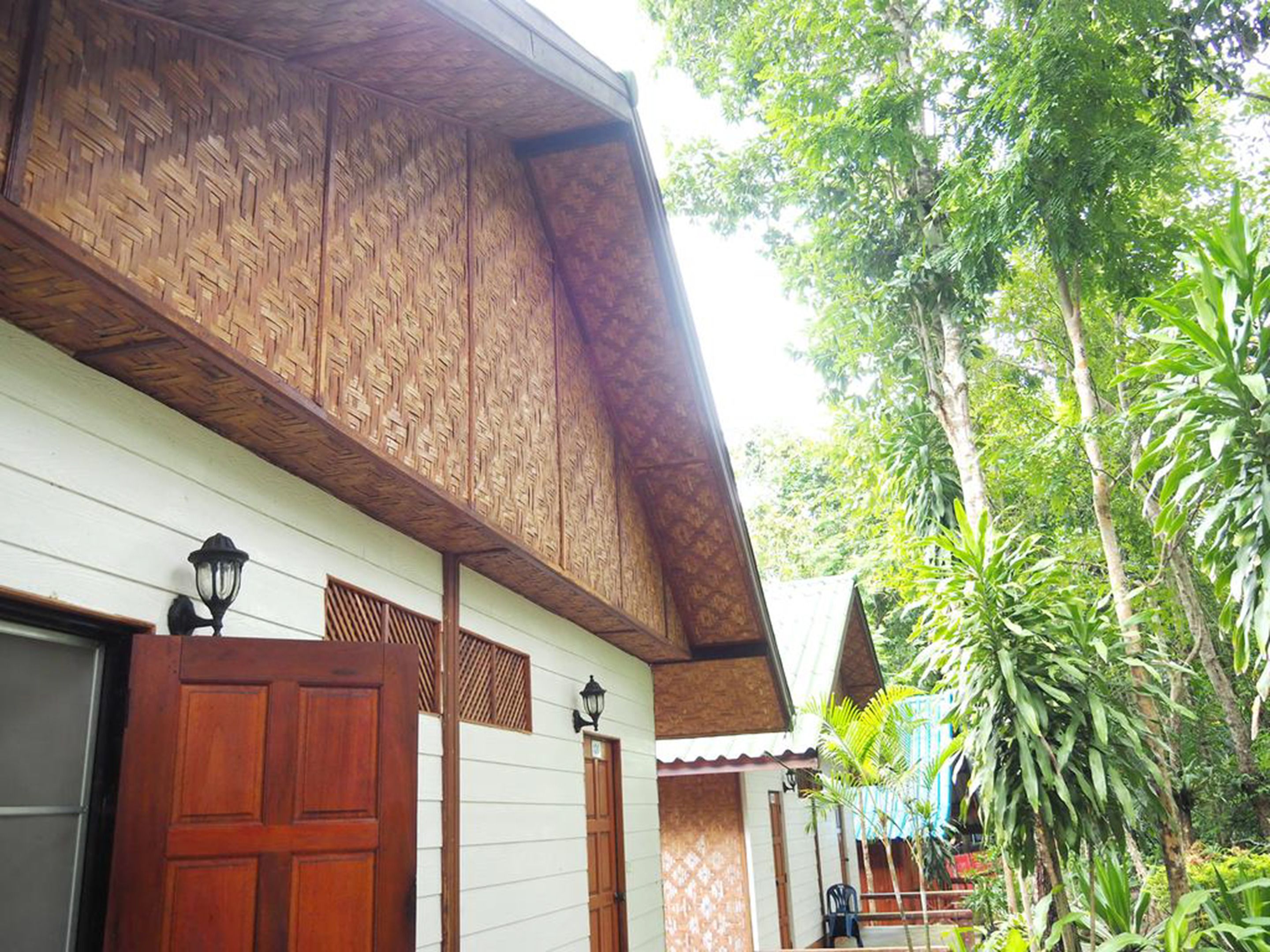 A traditional wooden building with a thatched roof, a wooden door, and a small porch area.