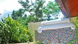 A wooden deck with potted plants, a tiled wall, and a view of trees. - Oopkaew Resort (Pua)