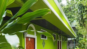 A green building with a red door, surrounded by lush greenery. - Oopkaew Resort (Pua)