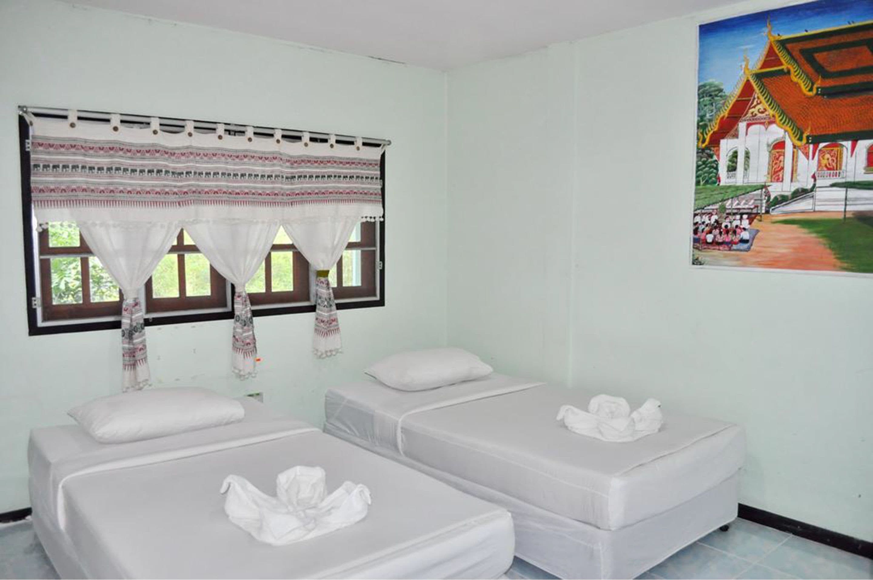 A room with two beds, a window with curtains, and a painting on the wall.