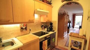 A kitchen with wooden cabinets, a stove, and a sink. There is a small table with a vase and a basket.