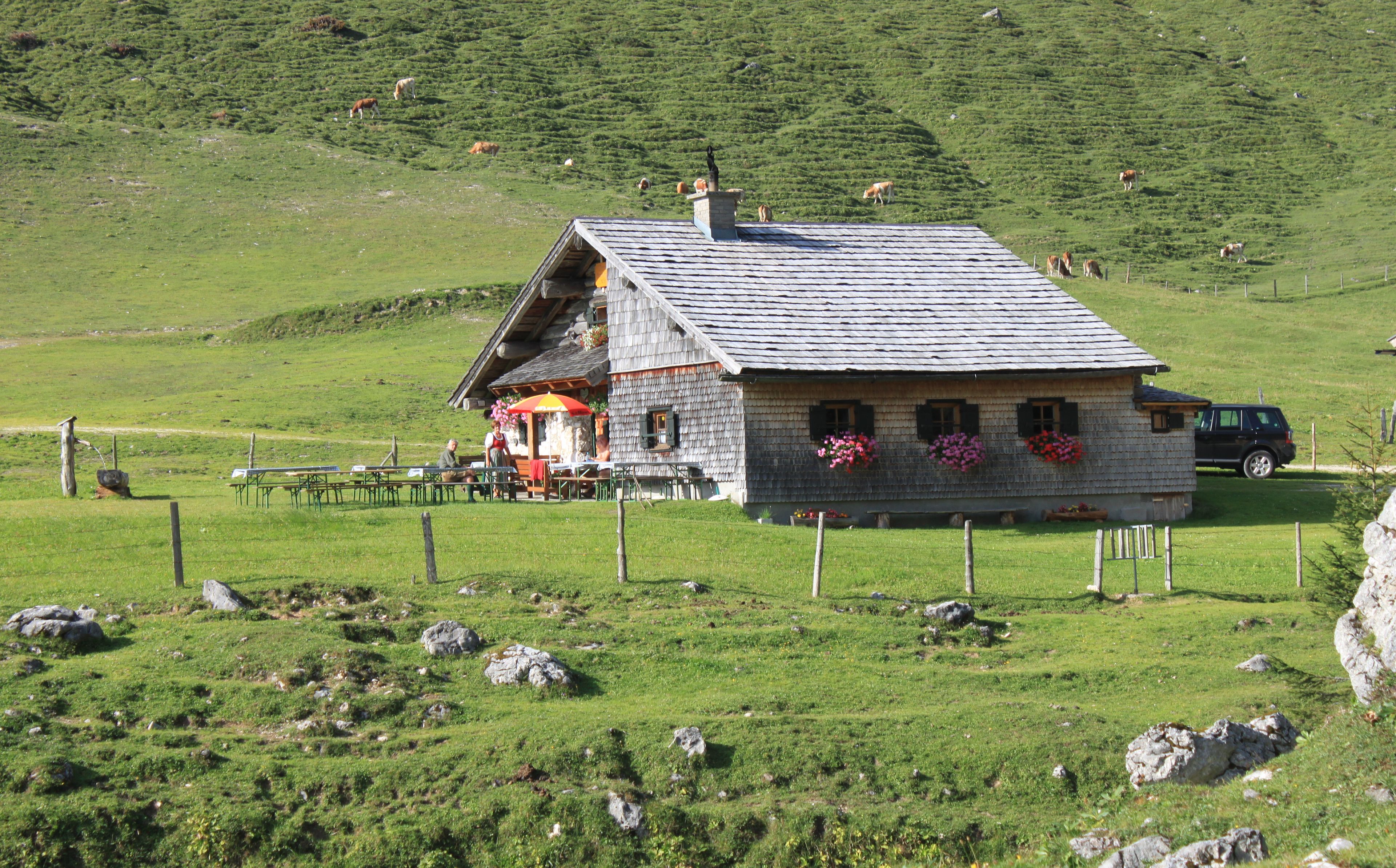 A rustic chalet with a sloped roof, a wooden deck, and flower boxes on the windows.