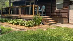Una casa de madera con porche, escalones y un pequeño jardín.
