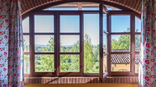 Una habitación con un amplio ventanal de arco que da a un paisaje verde.