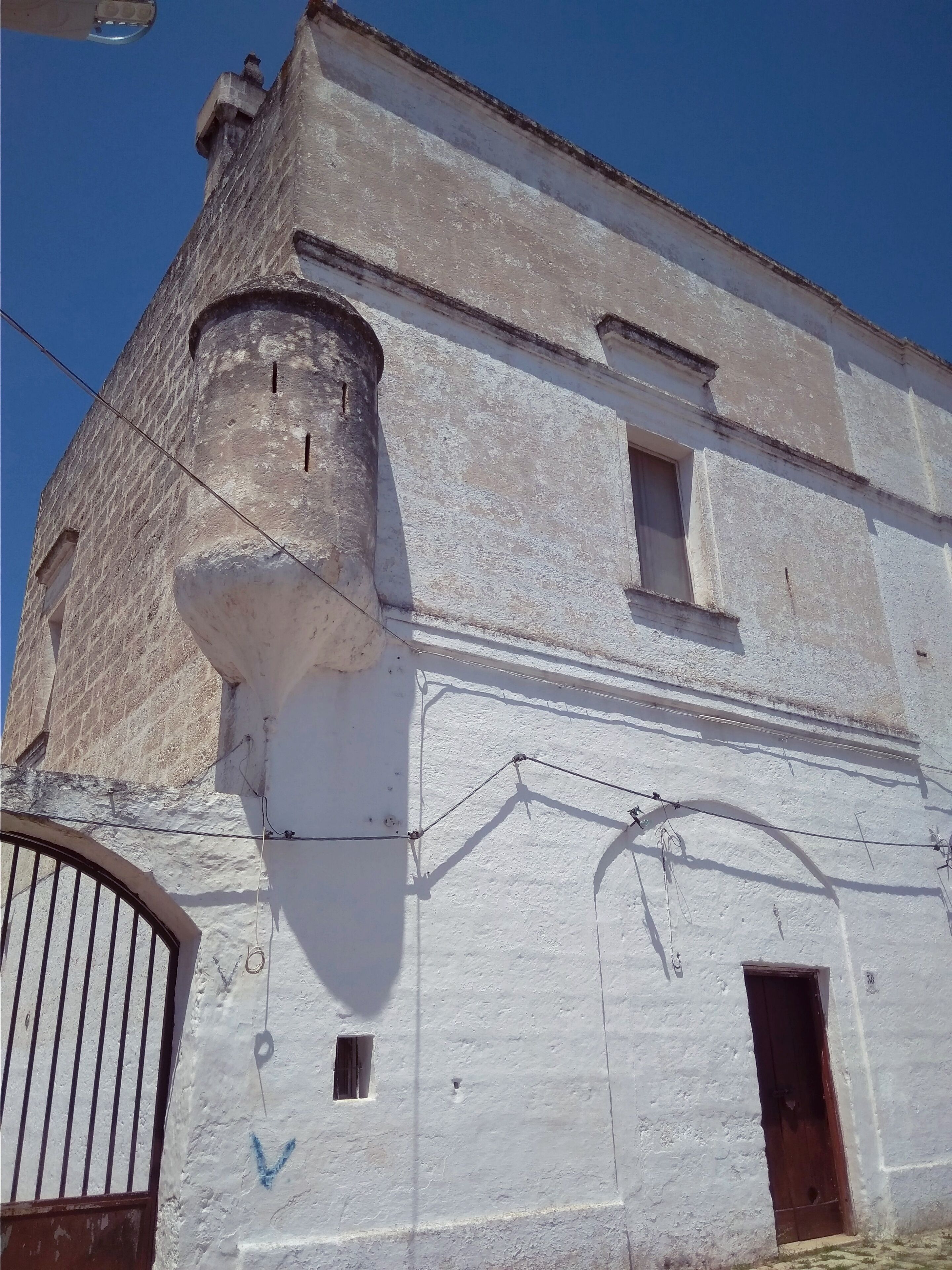 Un edificio con fachada blanca, una ventana visible y una puerta.