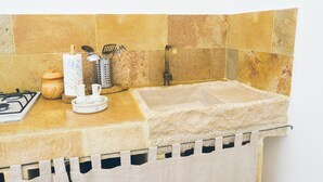 Una cocina con estufa a gas, un lavabo y diversos utensilios de cocina.