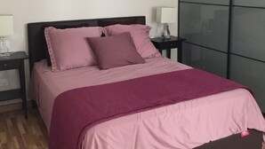A bedroom with a bed, two bedside tables, a hanging light, and a dark wall with a window. - Calle Guerrilleros, entre centro histórico y la zona del Corte Inglès (salamanca)