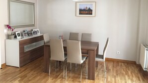 A dining area with a wooden table, four chairs, a white cabinet, and a framed picture on the wall. - Calle Guerrilleros, entre centro histórico y la zona del Corte Inglès (salamanca)