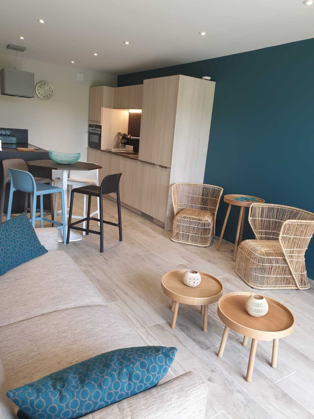 Un salon moderne avec un canapé, des fauteuils et un petit coin repas.