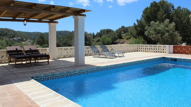 Un área de piscina con sillones de descanso y una pérgola.