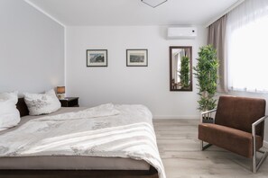 A bedroom with a bed, a brown chair, a nightstand, a mirror, and two framed pictures on the wall. - Sunny days in our dreamlike, beautiful Dresden! (Center) (Dresden)