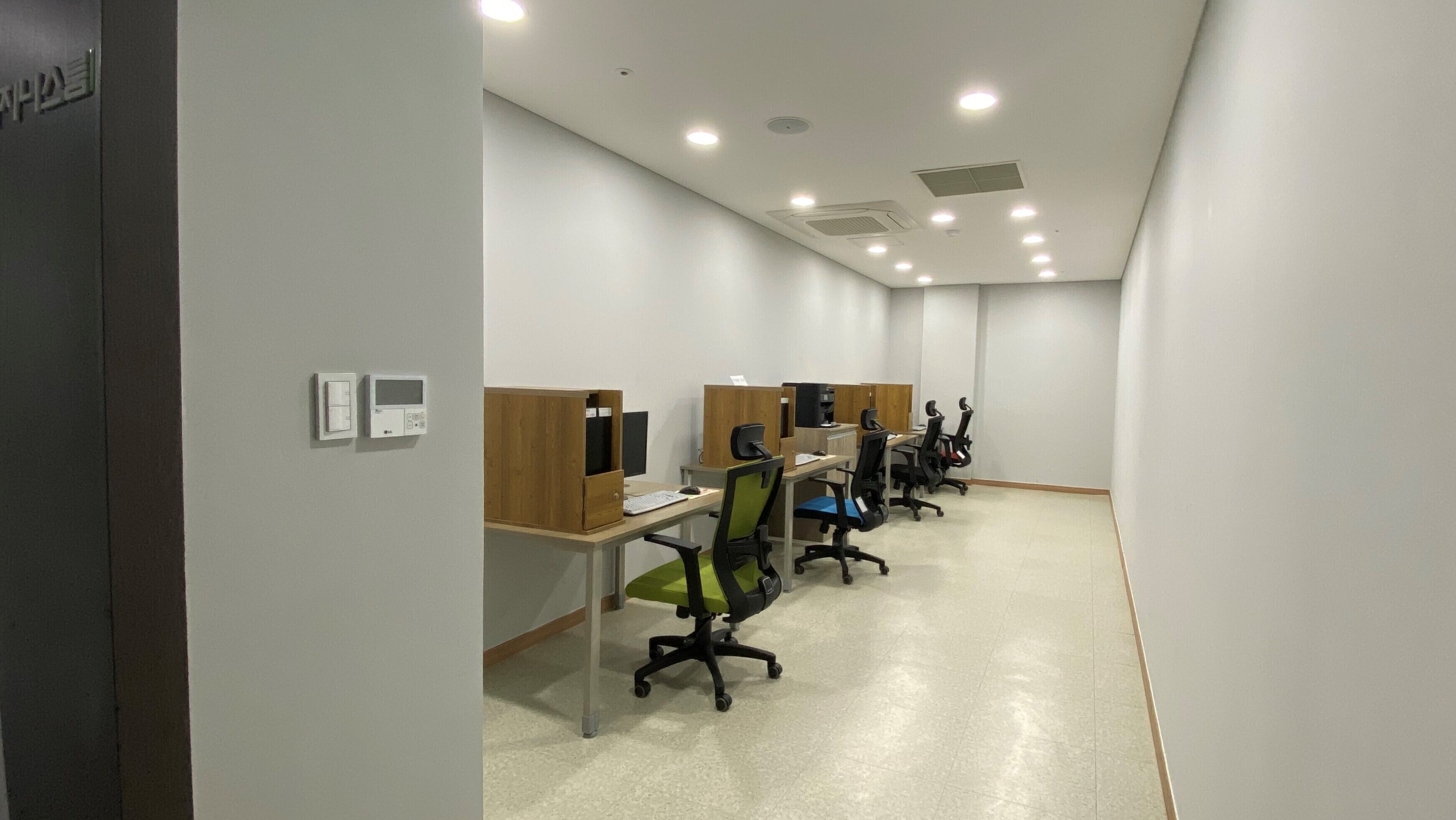Un espacio de oficina moderno con estaciones de trabajo individuales, cada una equipada con una computadora, teclado y silla.