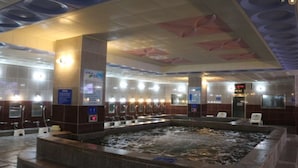Eine Hotelhalle mit einem zentralen Whirlpool-Bereich, verschiedenen Sitzgelegenheiten und einer außergewöhnlichen Deckenkonstruktion.